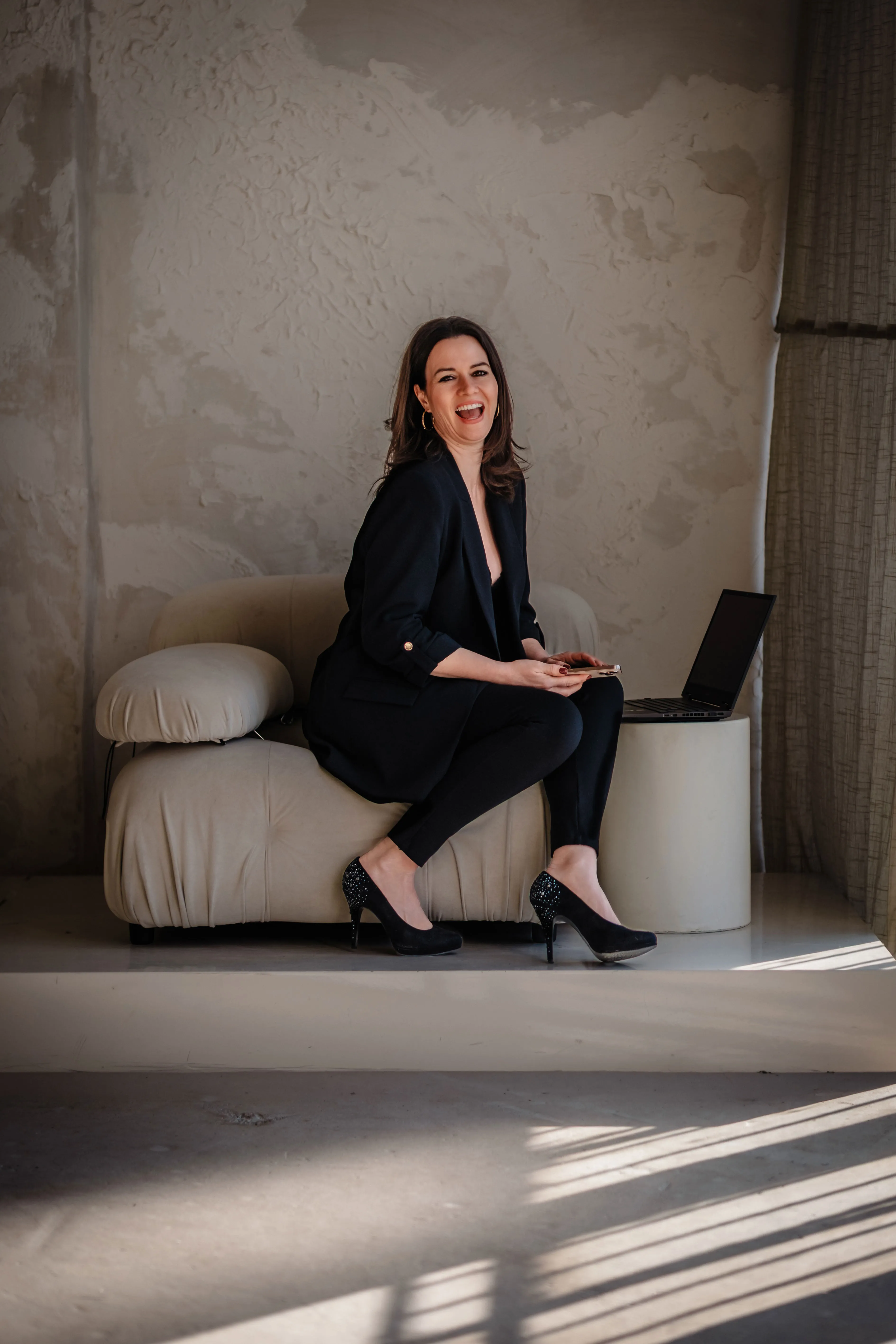 Sarah-Yasmin Hennessen sitzt lachend neben einem geöffneten Laptop.